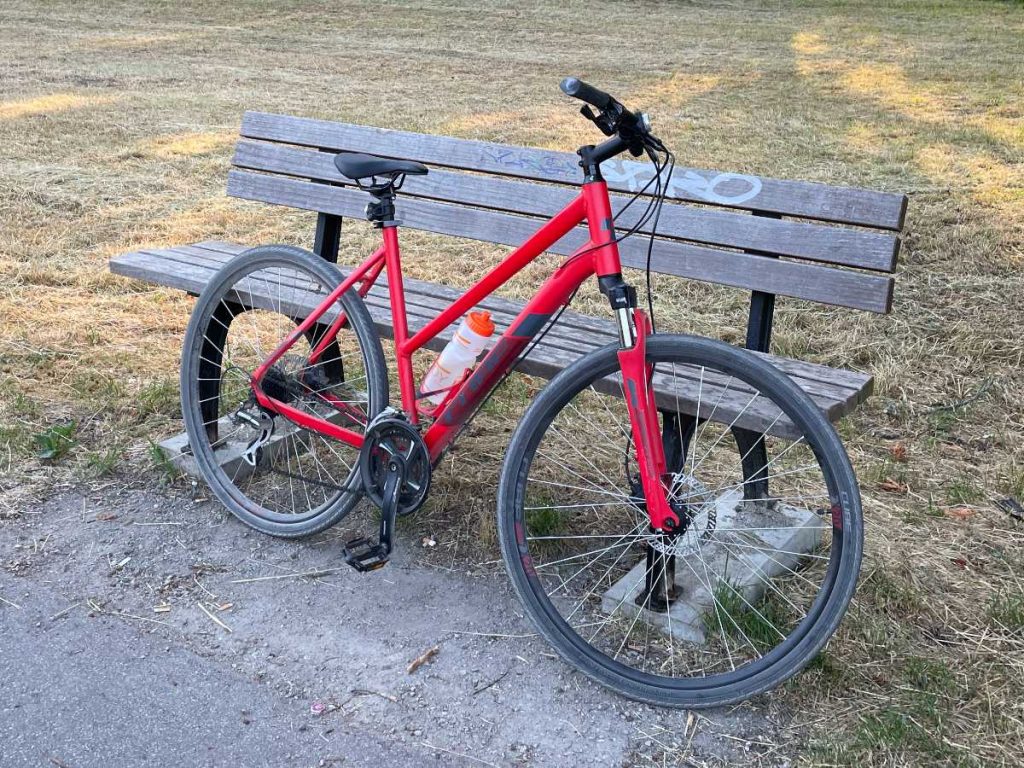 rotes Fahrrad an einer Bank angelehnt